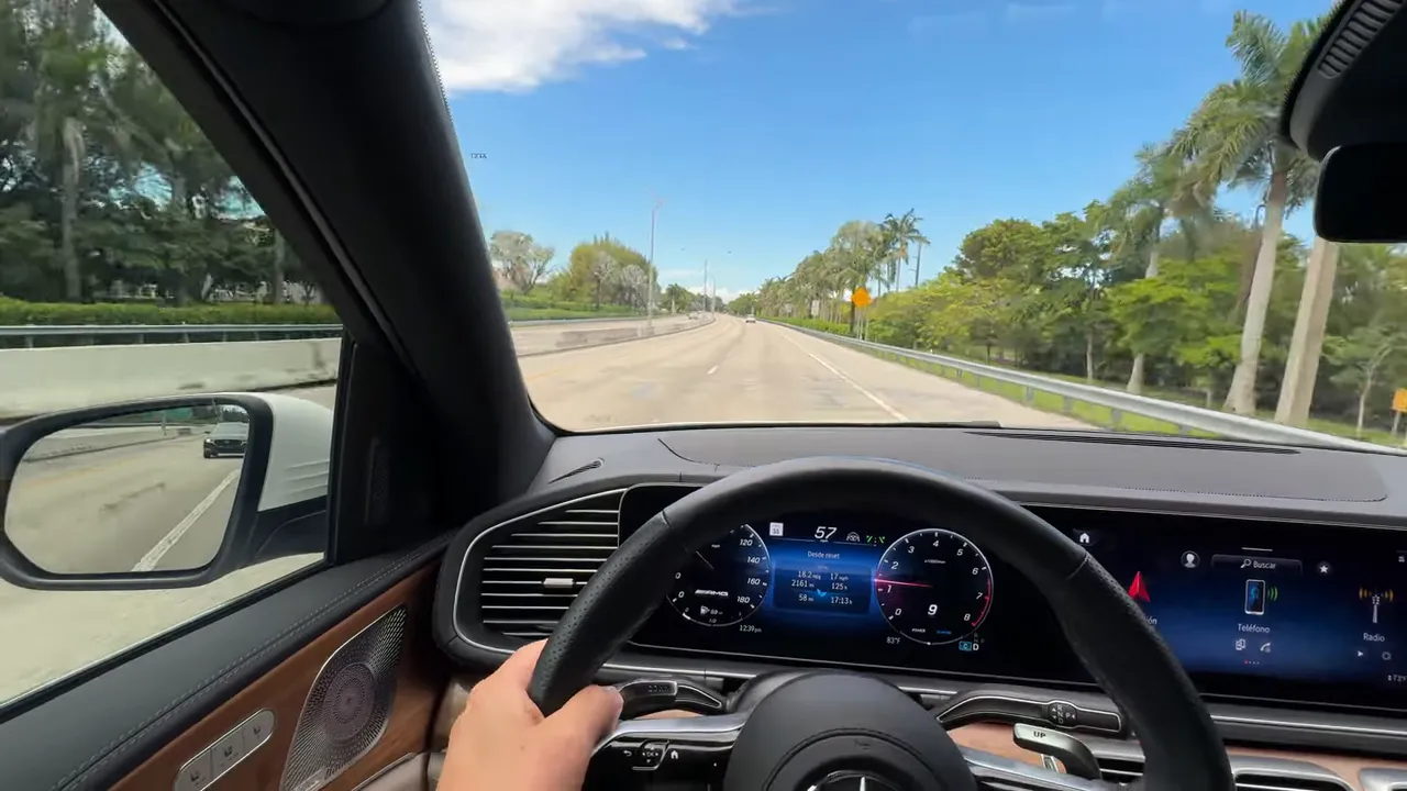 Espejo lateral izquierdo mostrando pequeña porción de la cola del auto y la carretera